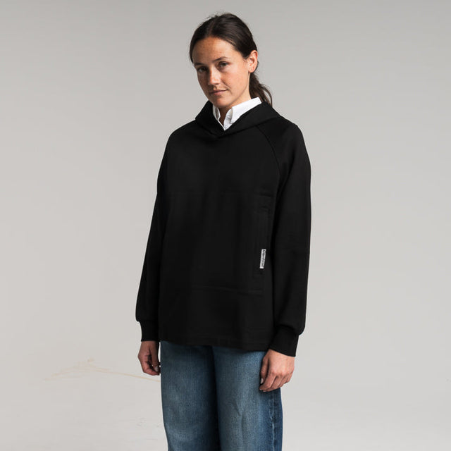 woman wearing a black hoodie and blue jeans on a plain background