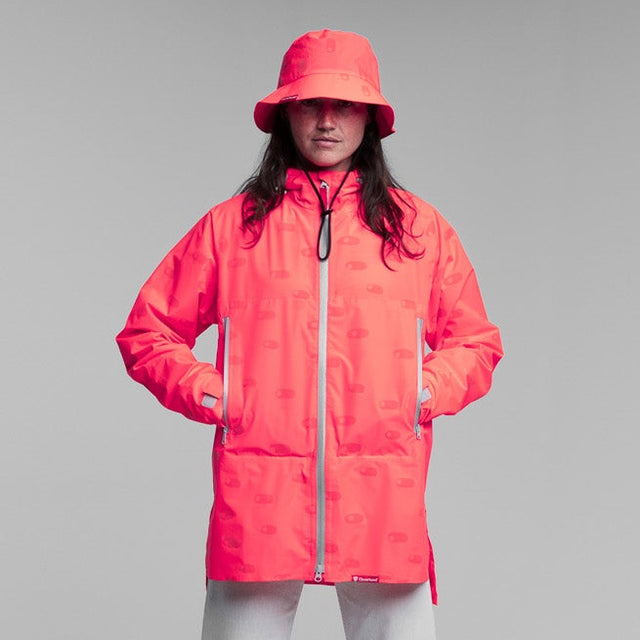Person wearing a bright pink reflective rain jacket and hat on a plain background