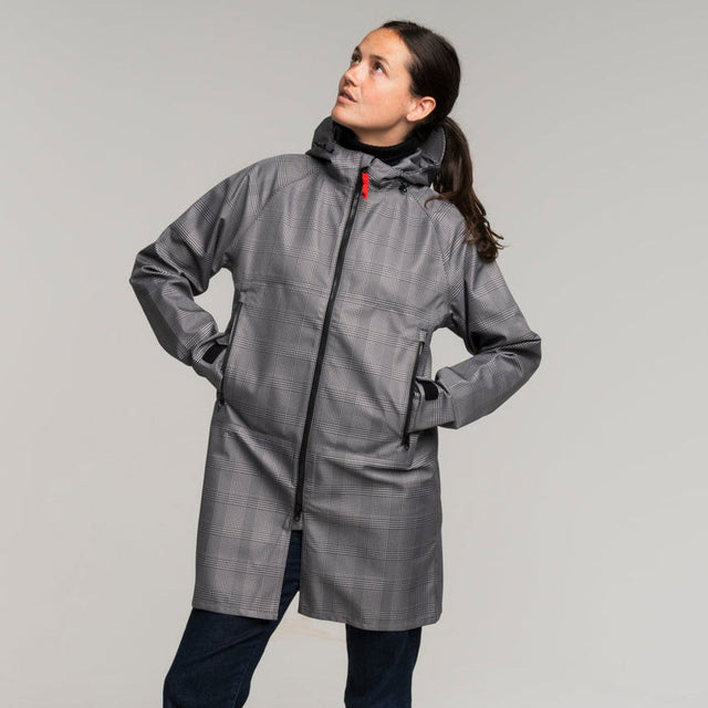 woman wearing a gray houndstooth trench coat standing against a white background