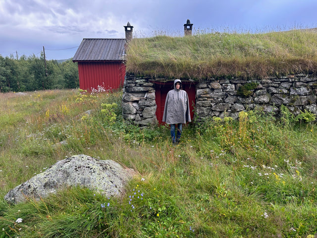 Cleverhood Urbanaut Rain Cape in front of grass covered building in Norway