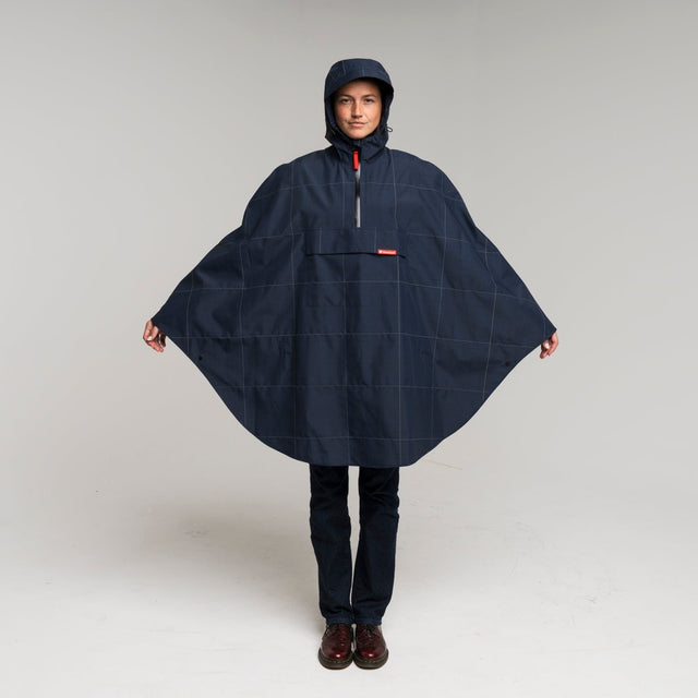 Person wearing a navy blue rain poncho on a white background